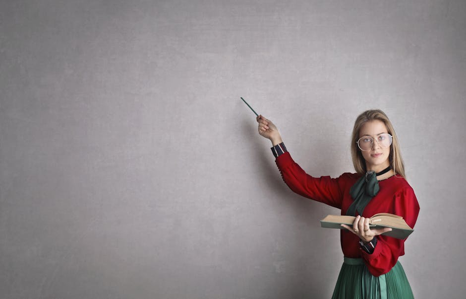 Female teacher pointing at a blank wall, holding a book, creating copyspace for educational content