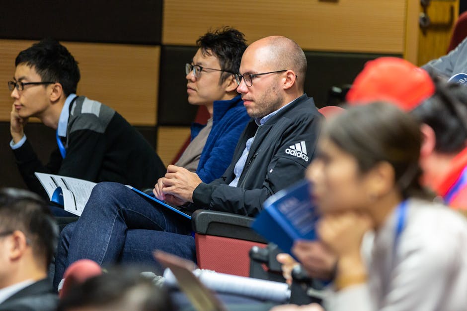 A diverse group of adults attentively listening to a lecture in an indoor conference setting